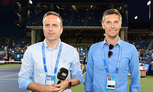 Two tennis journalists standing courtside at the Western & Southern Open with SK microphones and media credentials.
